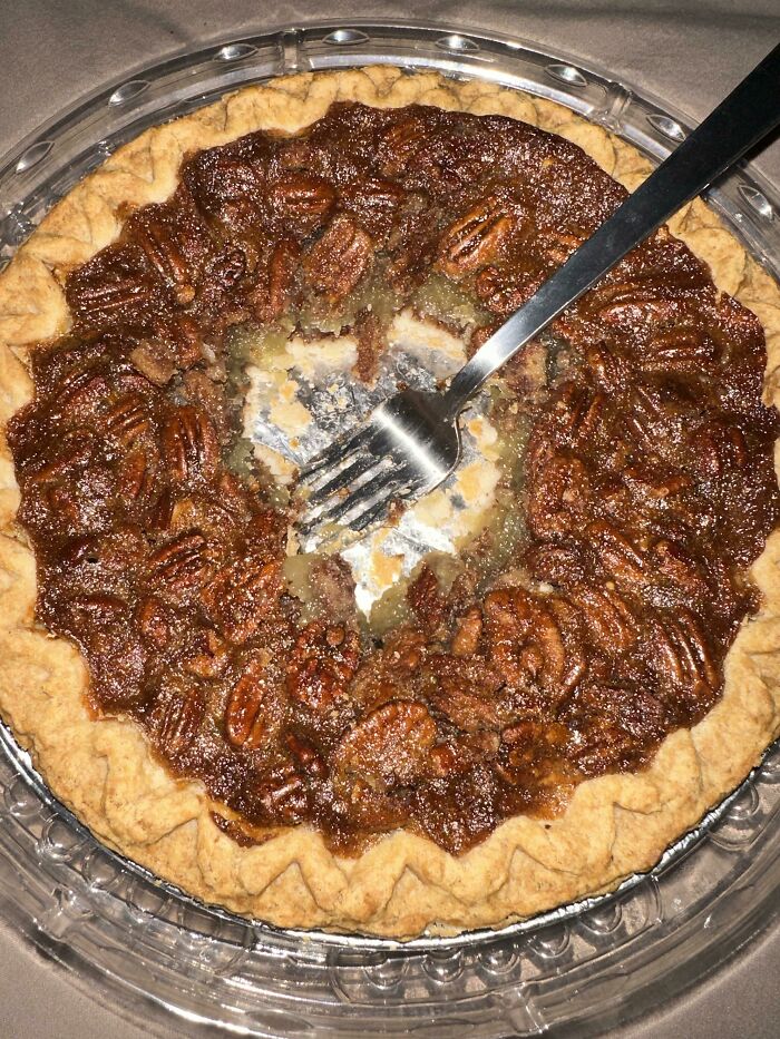 Pecan pie with unevenly eaten center, illustrating weaponized incompetence humorously with a fork left in the pie.