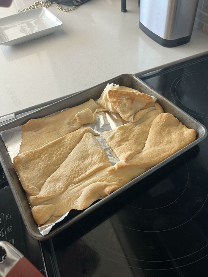 Baking mishap showing uneven dough on a tray, representing weaponized incompetence in cooking.
