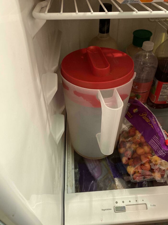 Pitcher with a red lid almost empty in the fridge, illustrating the idea of weaponized incompetence in household chores.