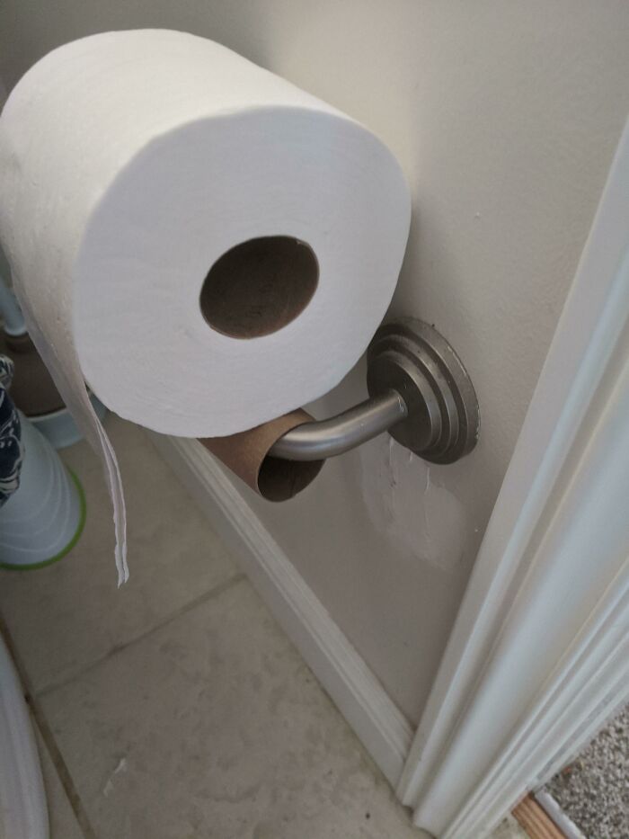 Toilet paper roll placed on top of an empty holder, illustrating weaponized incompetence in household tasks.
