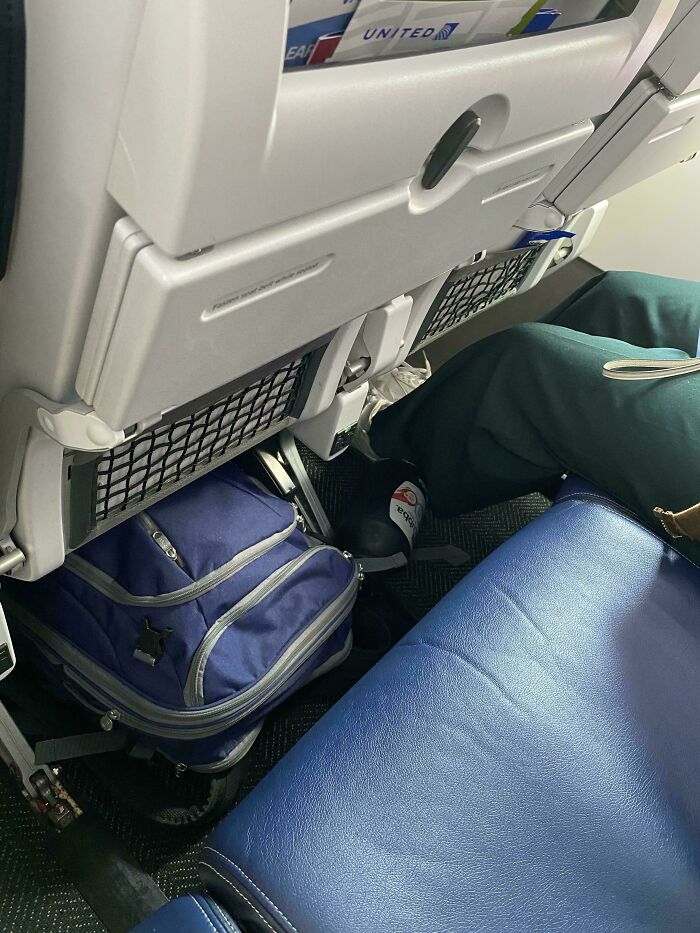 Airplane seat with passenger placing feet on storage area, illustrating annoying plane passengers.