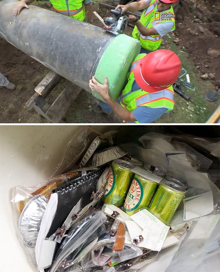 Workers opening a large historical time capsule filled with various preserved items and canned drinks.