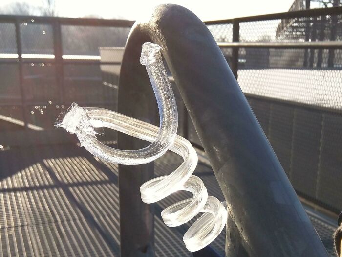 Ice formation twisted around a metal railing during a cold winter day.