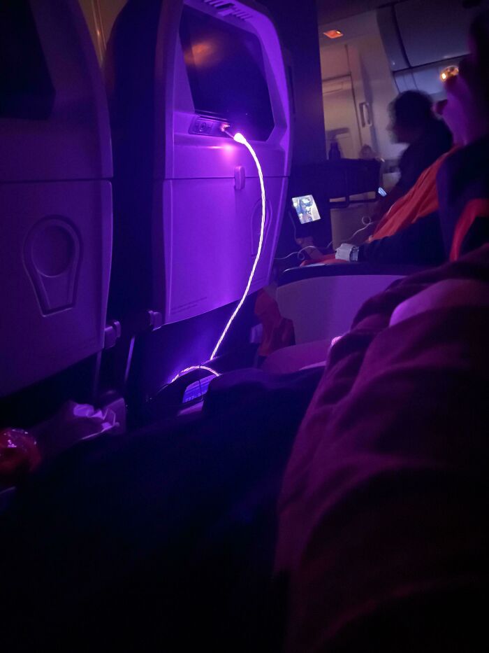 Bright purple LED cable on airplane seat causing annoyance to passengers.