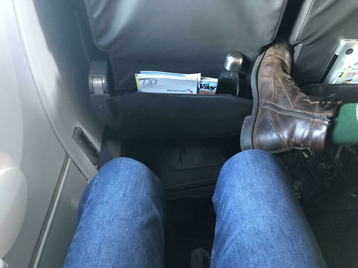 Close-up of a passenger's legs on a plane with another passenger's shoe invading their space, illustrating annoying-plane-passengers.