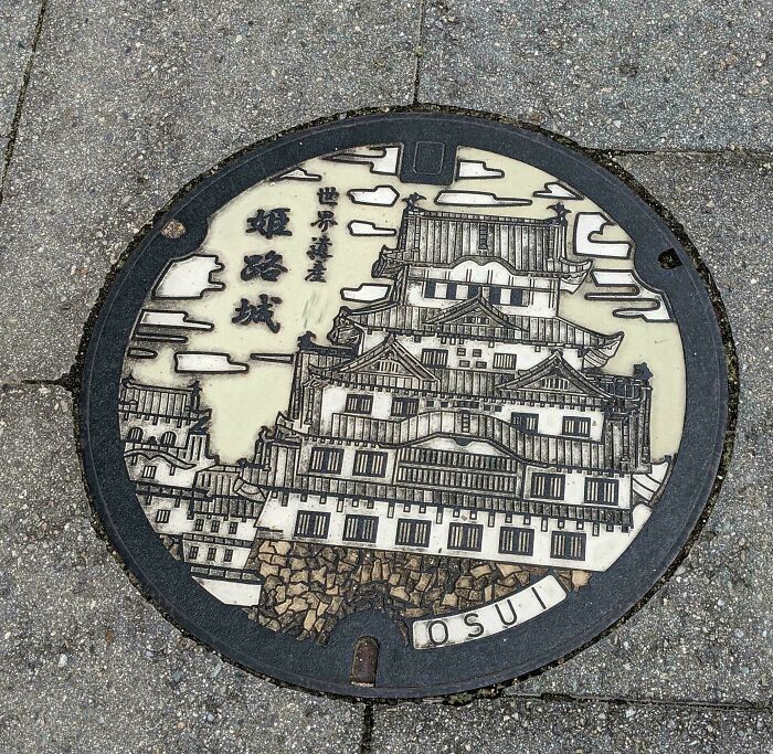 Decorative manhole cover featuring intricate design of a castle, showcasing designers' creativity and skill.
