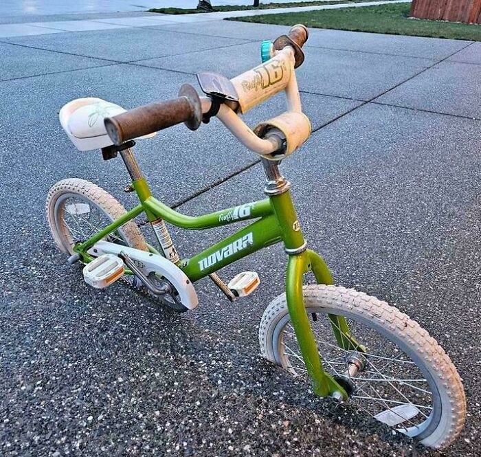 Green bicycle with handlebar and pedal alignment optical illusion on concrete, showcasing interesting not photoshopped image.