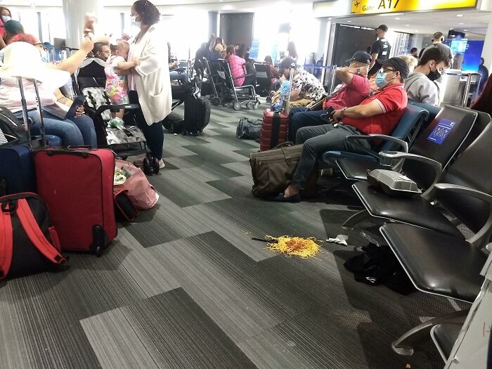 Passengers in airport gate area, one seat has spilled food, highlighting common annoying plane passengers behavior.