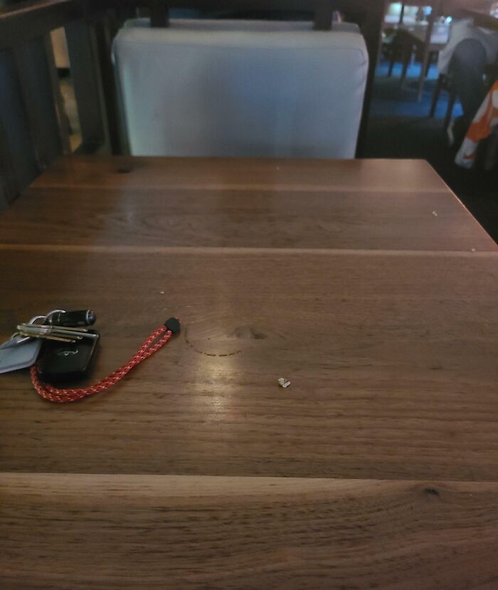 A set of keys left on an empty wooden table in a dimly lit restaurant.