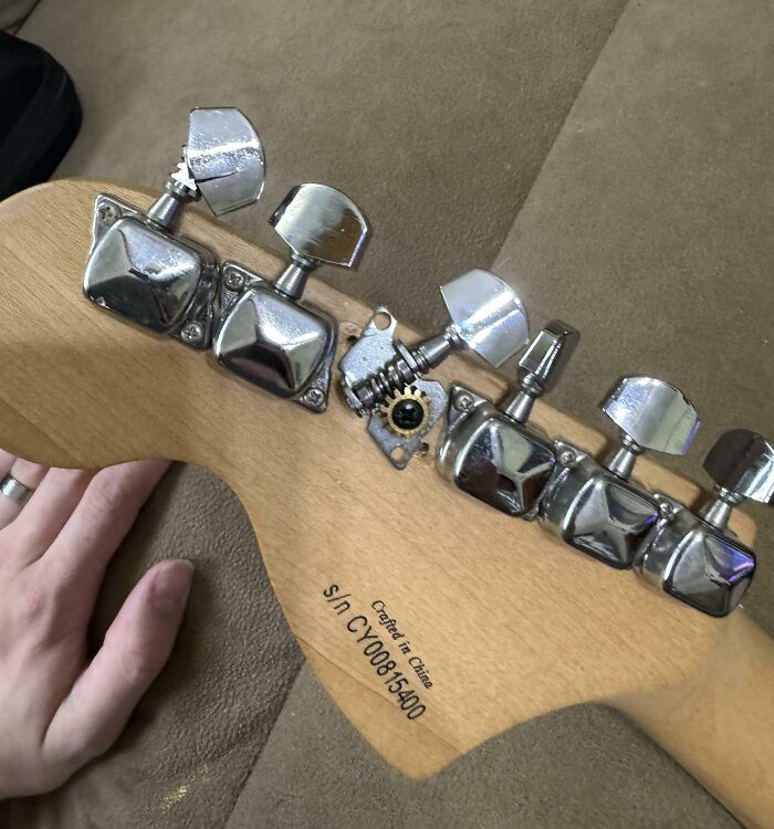 Guitar with one incorrect tuning peg, highlighting people being jerks by misplacing parts.