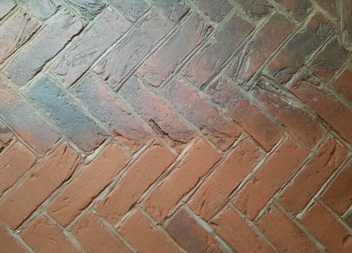 Before and after cleaning pictures of a herringbone brick floor showing noticeable contrast in cleanliness and color.