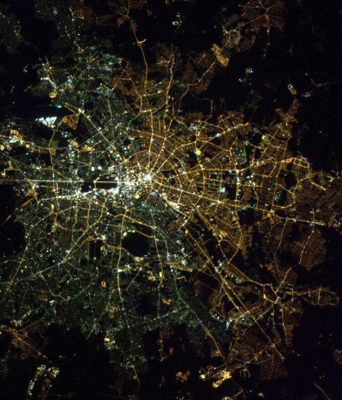 Aerial view of illuminated city map at night, showcasing intricate street patterns and glowing urban areas.