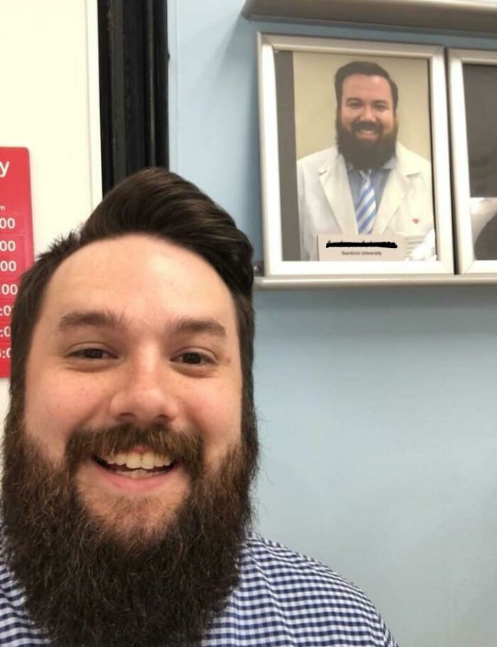 Man smiling next to a photo of his uncanny doppelganger.