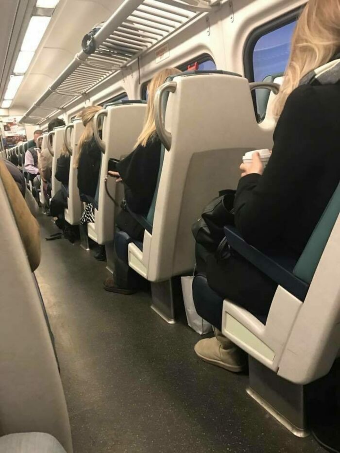 Train passengers with uncanny doppelgangers; all have similar hair and outfits, highlighting a glitch in the matrix effect.