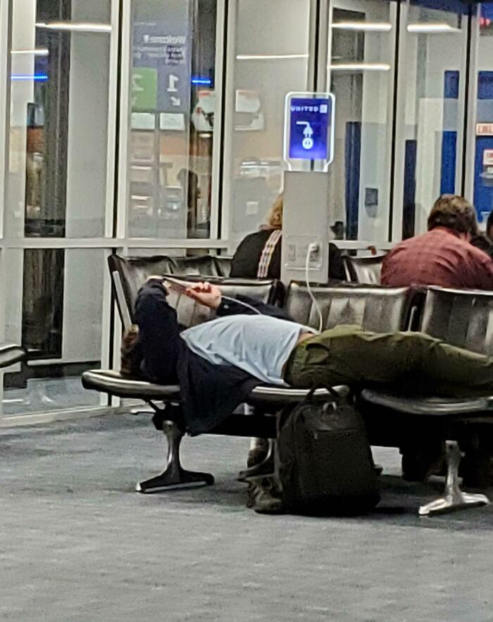 Passenger sprawled across airport chairs, embodying annoying plane passengers behavior.