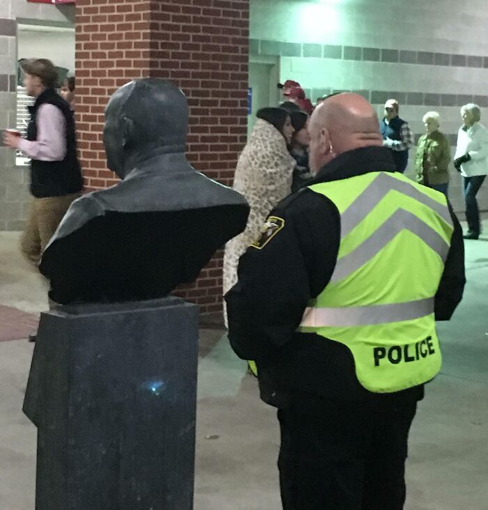 Police officer in front of statue, resembling an uncanny doppelganger.