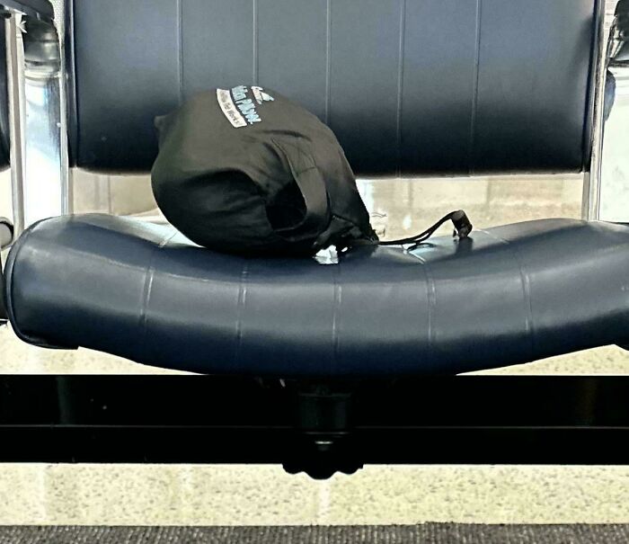 Black bag placed on a blue airplane seat, symbolizing annoying plane passengers.