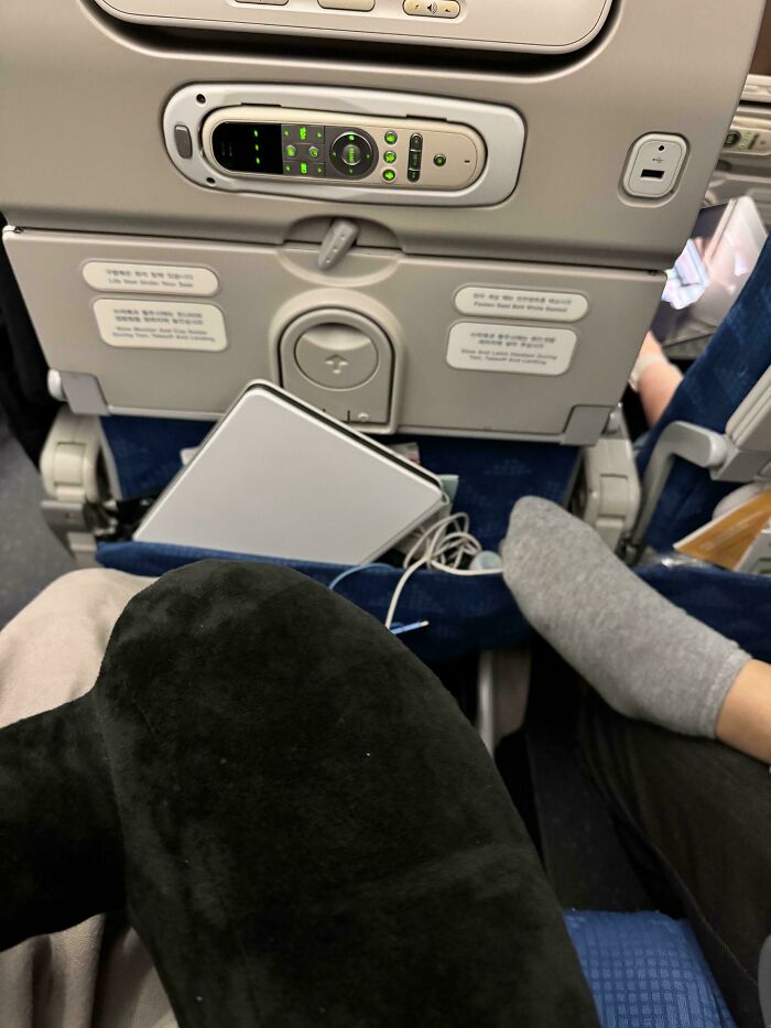 Feet on airplane seat back causing discomfort, highlighting annoying plane passengers.