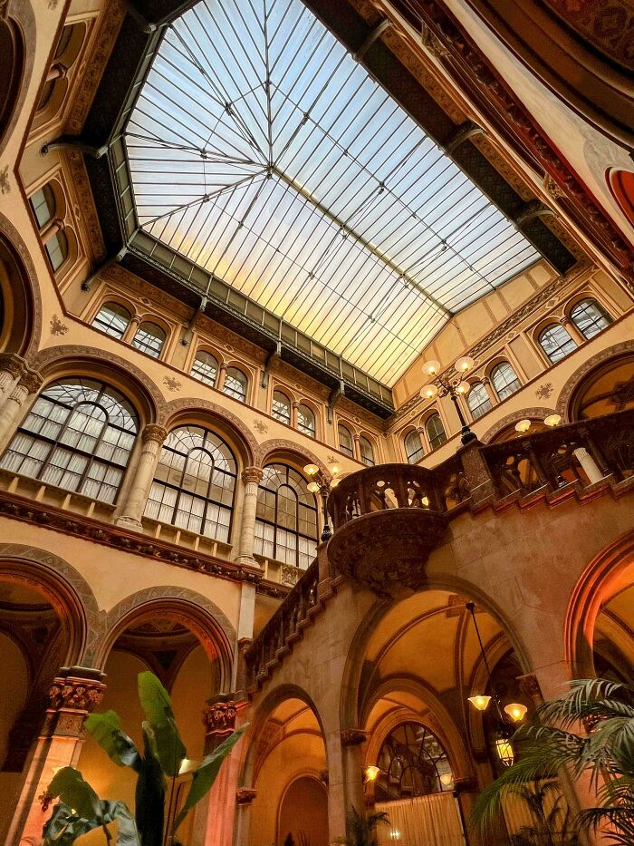 Intricate architectural feat of a historic building with large arched windows and a glass ceiling skylight.