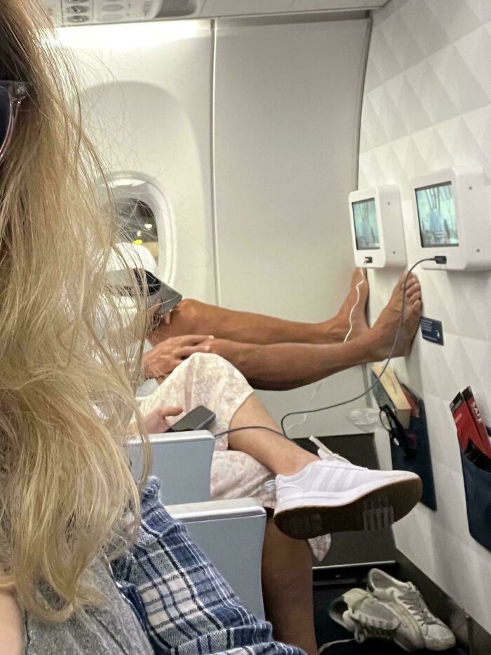 Passengers on a plane with feet resting on the wall, illustrating annoying behavior during flight.