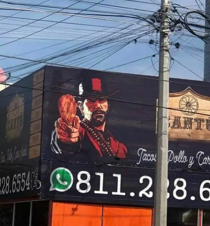 A bold mural on a shop wall depicts a cowboy pointing a chicken drumstick, catching the eye with its artistic flair.