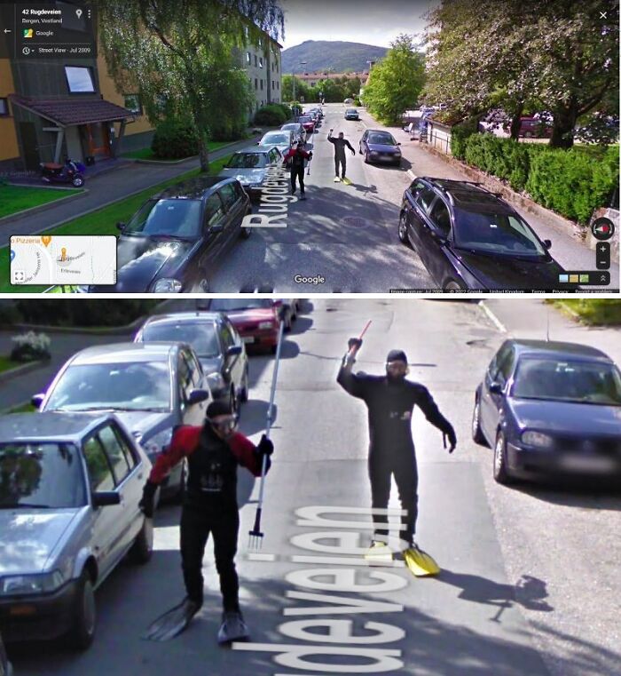Two people in scuba gear and flippers walking down a street, captured on Google Street View.