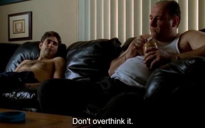 Two men lounging on a leather couch, one holding a jar. Text reads, "Don't overthink it." 90s moment vibe.
