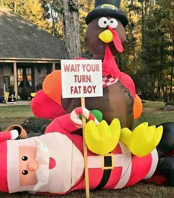 Thanksgiving home decoration featuring an inflatable turkey holding a humorous sign over Santa.