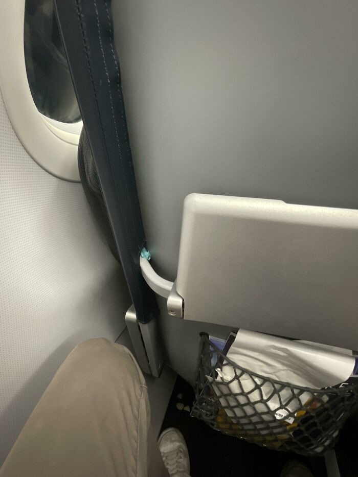 Passenger's leg cramped in tight airplane seat, illustrating annoying plane passengers scenario.