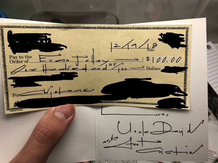 A handwritten check with elegant penmanship displayed on a note.