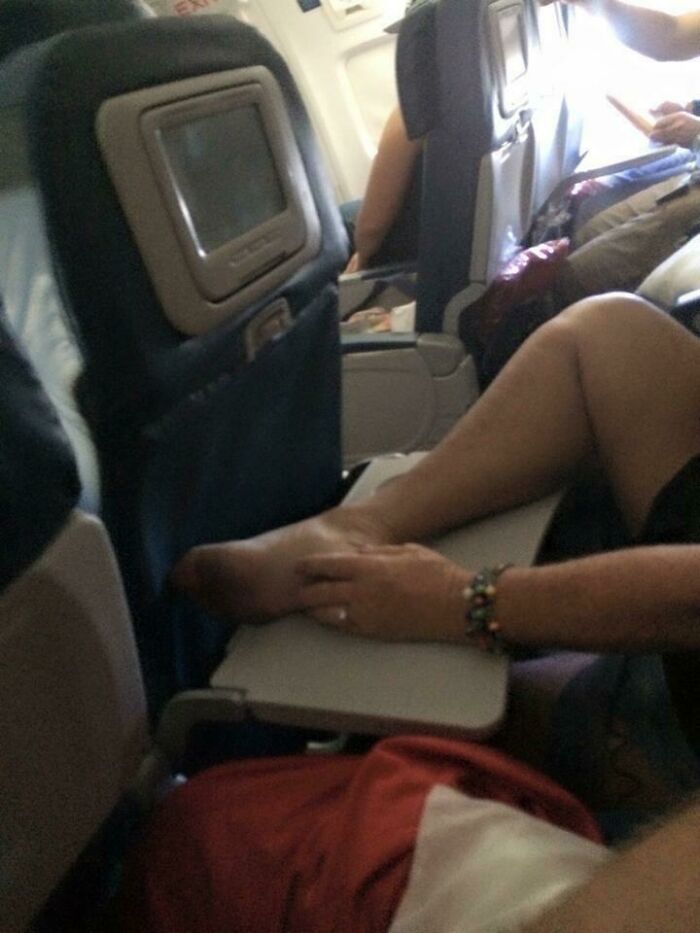 Bare feet on airplane tray table, exemplifying annoying plane passengers behavior.