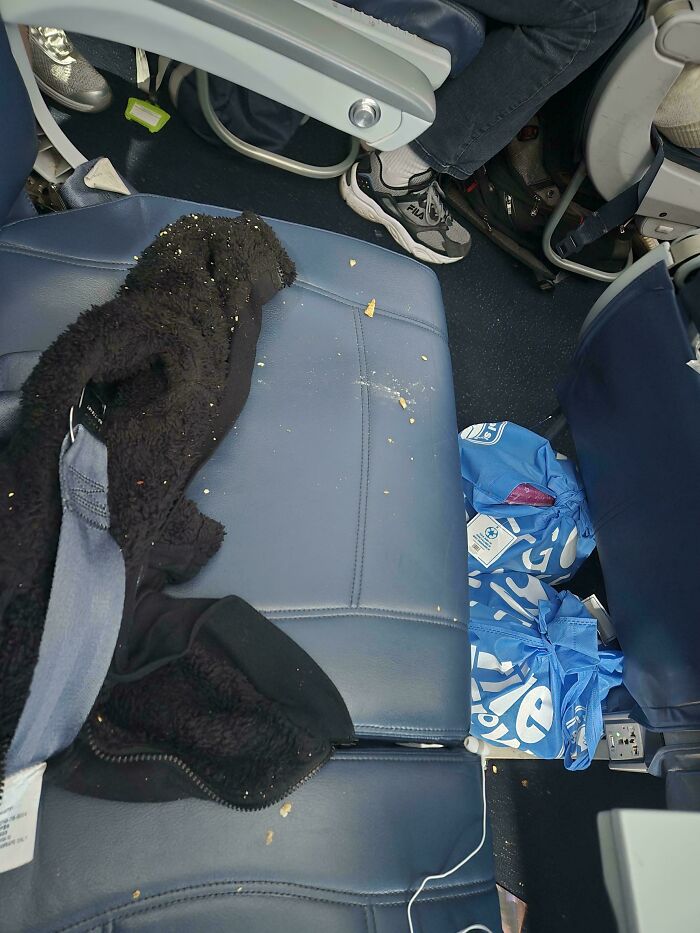 Messy airplane seat with crumbs and trash, illustrating annoying plane passengers.
