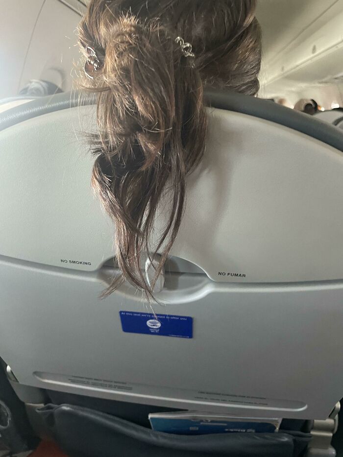 Hair draped over airplane seat from annoying plane passenger.