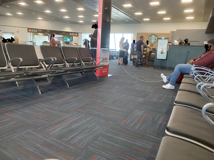 Airport seating area with a long charging cable strewn across the floor, a scene common among annoying plane passengers.
