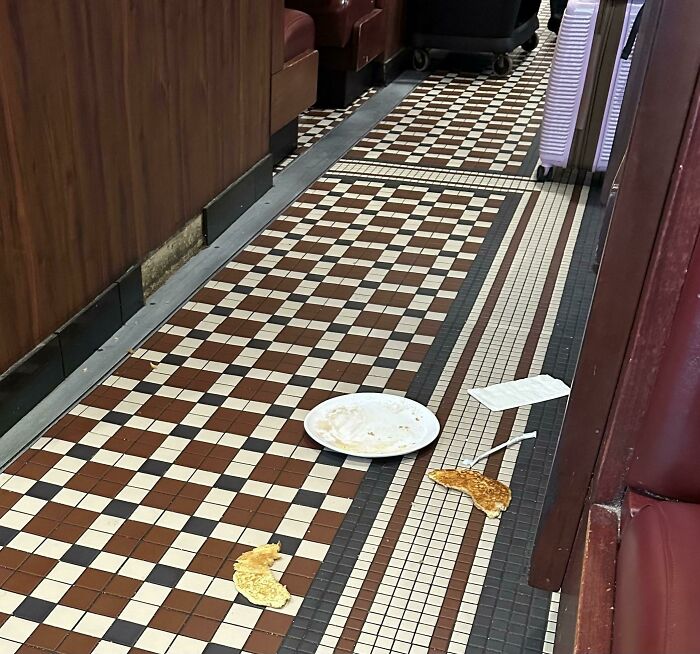 Messy airplane aisle with food and a plate on the floor, symbolizing annoying plane passengers.