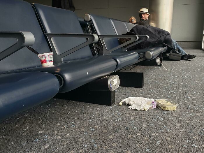 Annoying plane passengers leave trash and food containers scattered under airport seating.