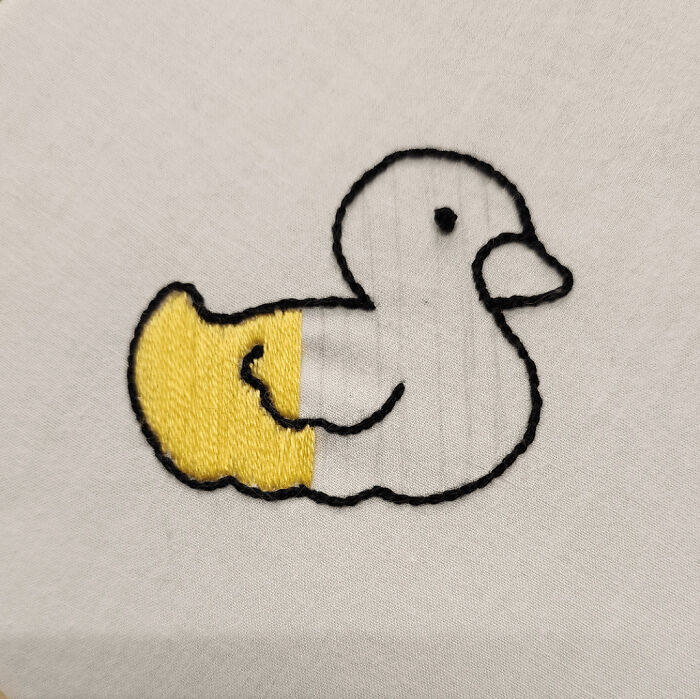 Partial yellow and black thread embroidery design of a duck on white fabric showcasing beautiful embroidery designs.