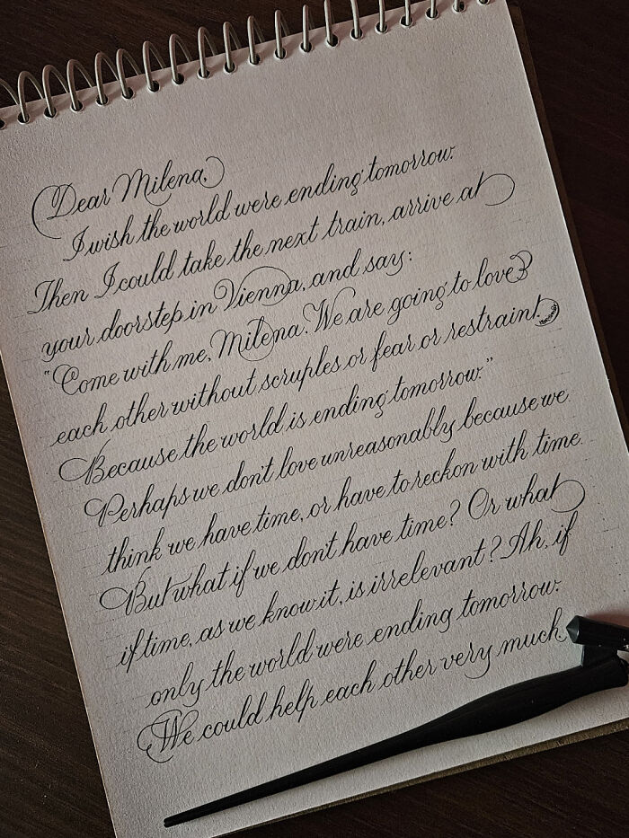 Elegant handwritten letter showcasing remarkable handwriting skills on a notepad, with calligraphy pen beside it.