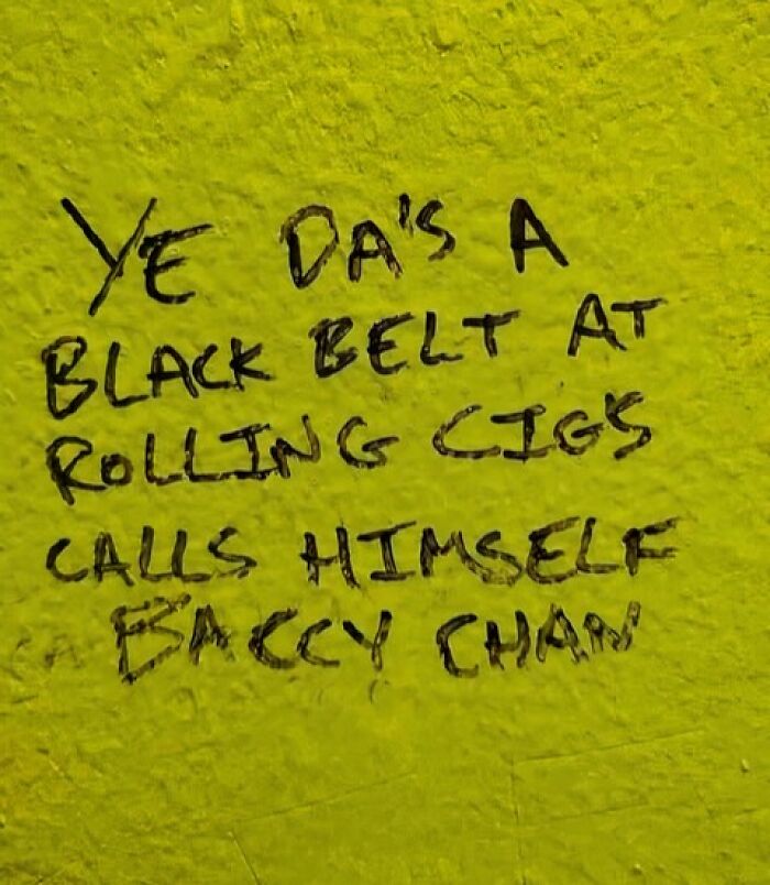 Graffiti on a yellow wall humorously describes a black belt in rolling cigarettes, showcasing Ireland's charm.