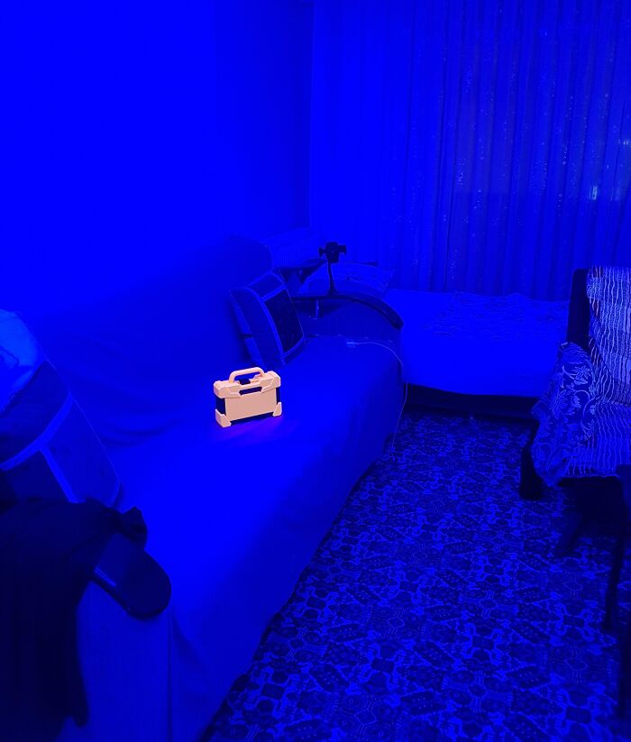A room bathed in blue light with a glowing yellow object on a sofa, showcasing an interesting, not-Photoshopped effect.