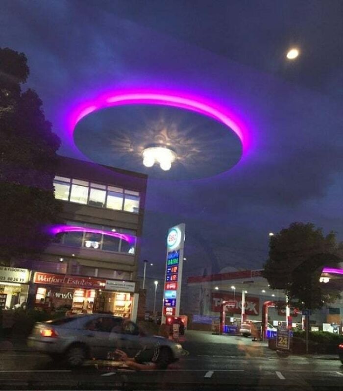 A purple glowing ring appears in the cloudy night sky above a gas station, creating an interesting not-photoshopped effect.