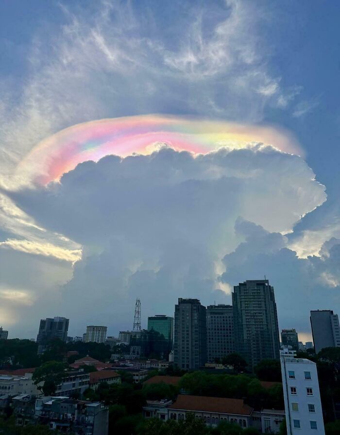 Vibrant rainbow cloud over city skyline, showcasing interesting not photoshopped phenomena.