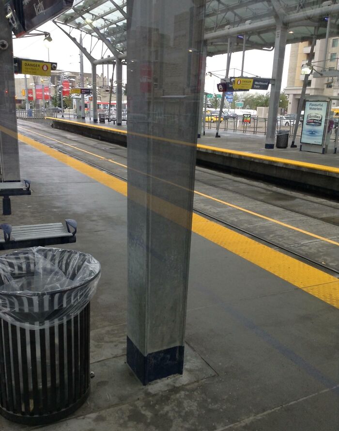A seamless reflection of a pole creates an interesting optical illusion at a train station, not photoshopped.