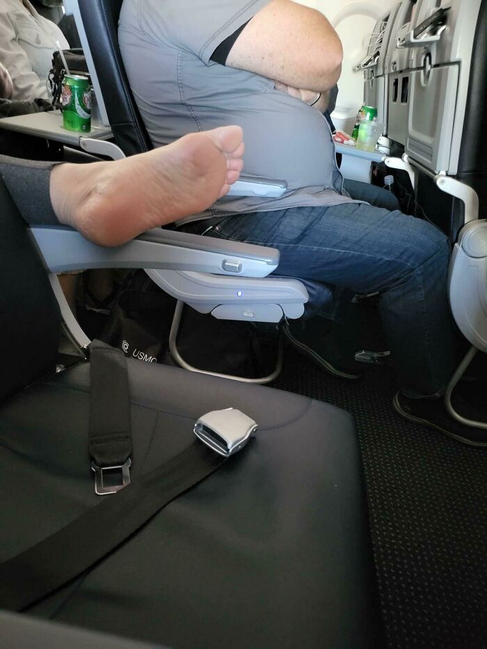Bare foot of a passenger on plane armrest, illustrating annoying-plane-passengers behavior.