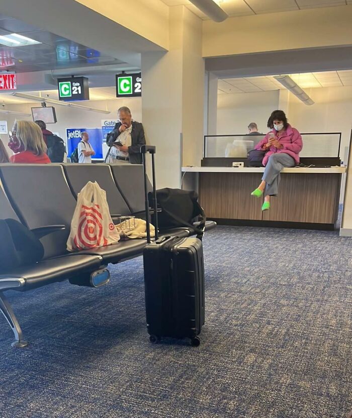 Passengers at an airport gate, one sitting on a counter, another holding a boarding pass.