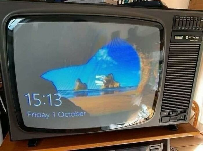 Old television displaying a computer's beach and ocean desktop background with the time 15:13 visible.