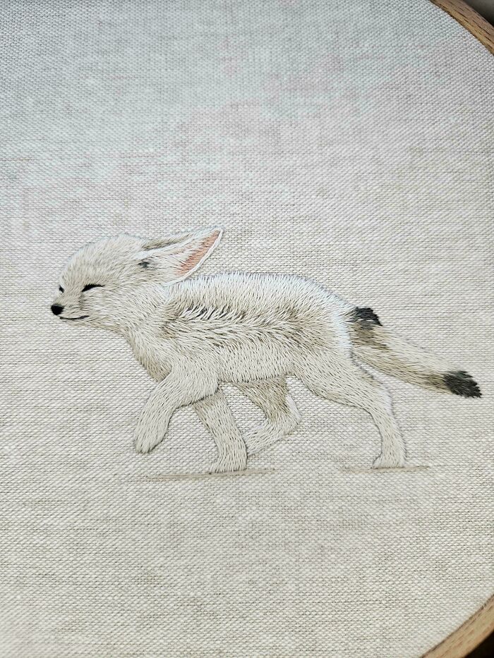 Embroidery design of a small white fox walking, showcasing detailed and beautiful embroidery stitches on fabric.