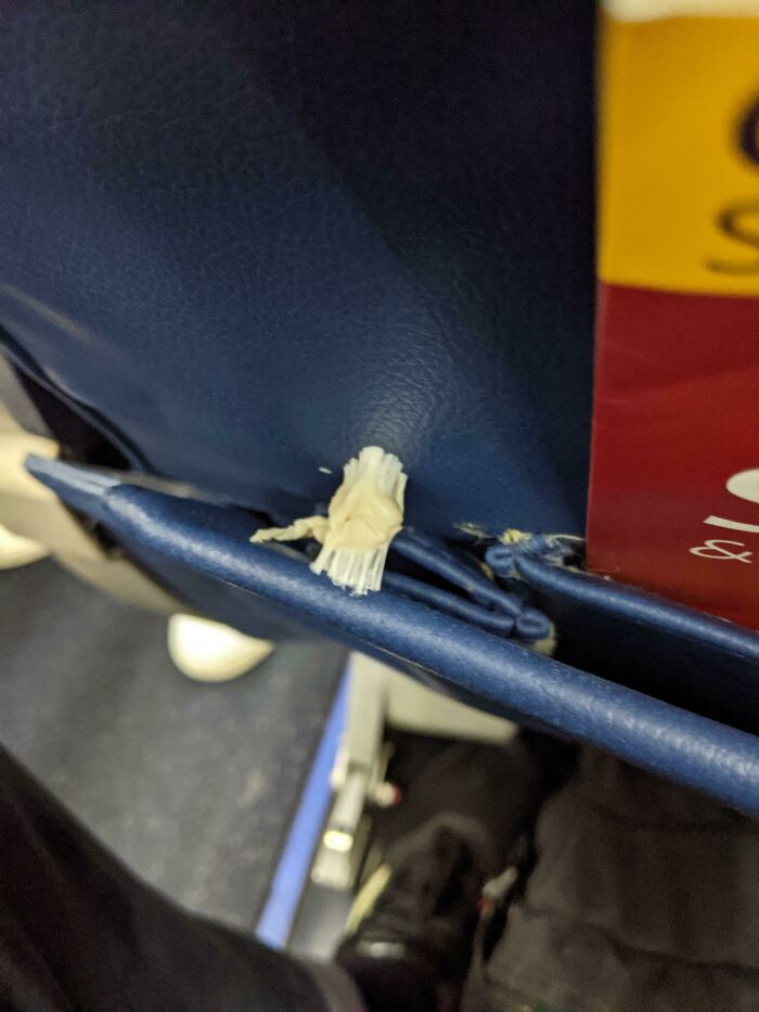 Seatback with chewed gum stuck on it, illustrating annoying plane passengers' behavior.