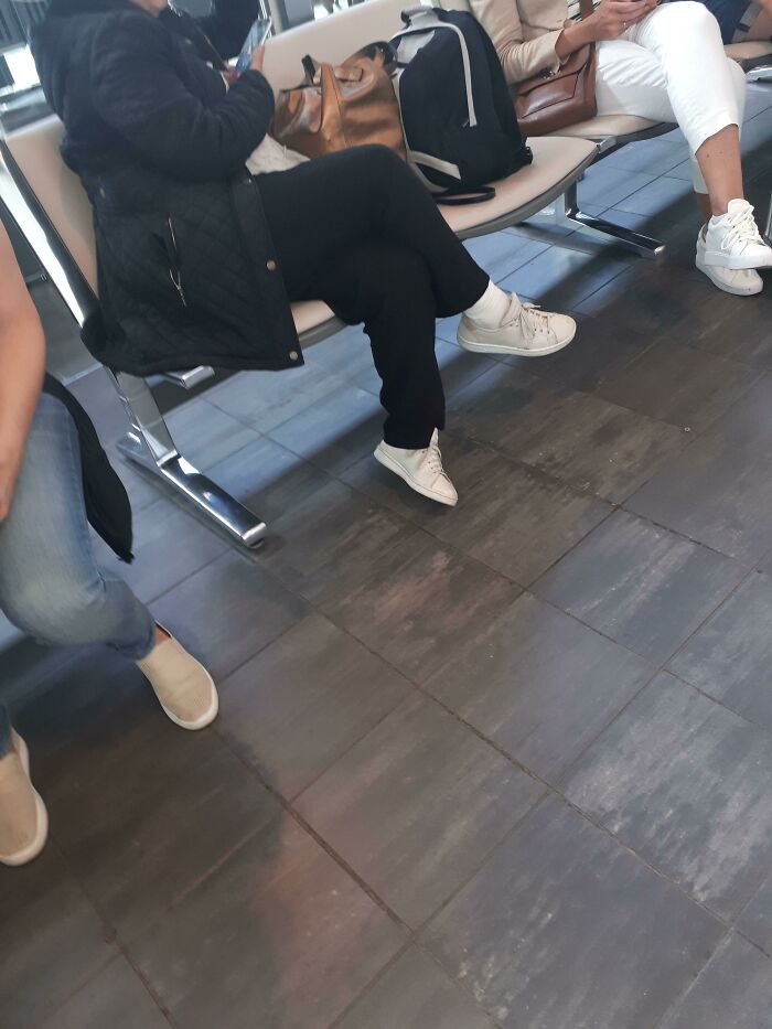 People sitting in an airport lounge, with bags on the seats, capturing behaviors of annoying plane passengers.