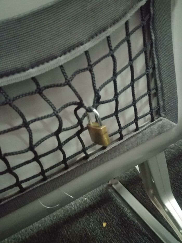 Padlock in airplane seat pocket, highlighting annoying plane passengers' unusual behavior.